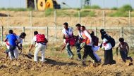 An injured Palestinian demonstrator is being moved away from the site after the intervention of Israeli forces during a demonstration within the 
