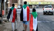 Sudanese demonstrators wear their national flag as they celebrate in Khartoum early on August 3, 2019, after Sudan's ruling generals and protest leaders reached a 
