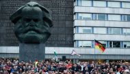 Right-wing demonstrators march past a sculpture of Karl Marx in Chemnitz, eastern Germany, on August 27, 2018, following the death of a 35-year-old German national who died in hospital after a 