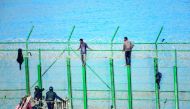 Two migrants force their way into the Spanish territory of Ceuta on August 30, 2018. Over 150 migrants made their way into Ceuta after storming a barbed-wire border fence with Morocco. AFP / Antonio Sempere