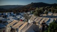 A migrant stands outside amid tents at the official refugee camp of Moria on the Greek island of Lesbos, on August 31, 2019.  AFP / ANGELOS TZORTZINIS
