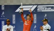 Ferrari's Charles Leclerc celebrates with a trophy on the podium after winning the race as he applauded by second placed Mercedes' Lewis Hamilton and third placed Mercedes' Valtteri Bottas REUTERS/Johanna Geron