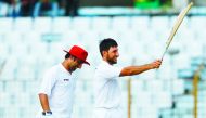 Afghanistan's cricketer Rahman Shah (R) raises his bat to celebrate scoring a century (100 runs) during the first day of the one-off cricket Test match between Bangladesh and Afghanistan at the Zohur Ahmed Chowdhury Stadium in Chittagong on September 5, 2