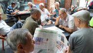 A man reads a newspaper as others play checkers in Singapore, January 16, 2018. Reuters/Calvin Wong