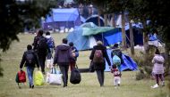 People and children leave after the evacuation, by French gendarmes, of the Grande Synthe migrant camp, northern France, on September 17, 2019. / AFP / FRANCOIS LO PRESTI 