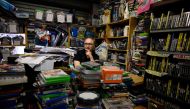 A shopkeeper sits amongst his stock of films and video games at his stall on Peterborough Market in Peterborough city centre, central England on September 26, 2019. AFP / Oli Scarff