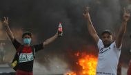 Iraqi demonstrators gesture next to a tyre fire during a demonstration against state corruption, failing public services, and unemployment, in the Iraqi capital Baghdad on October 5, 2019. AFP / AHMAD AL-RUBAYE