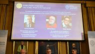 Members of the Nobel Committee for Physics (Bottom L-R) Chair of the Nobel Committee Mats Larsson, Secretary General of the Academy Goran K Hansson, and Ulf Danielsson sit in front of a screen displaying the portraits of the winners of the 2019 Nobel Priz