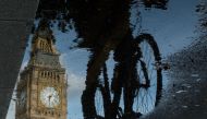 Big Ben is reflected in a puddle as a cyclist rides by in London on 27 June, 2016. AFP / Leon Neal