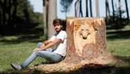 Sculptor Andrea Gandini is pictured next a sculpture of a wolf's face from a dead tree stump in the Villa Pamphili park, Rome, Italy, October 18, 2019. Picture taken October 18, 2019 REUTERS/Remo Casilli