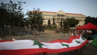 A long banner made up of Lebanese national flags hangs on barbed wire in front of the government headquarters, known as the Grand Serail, in the capital Beirut's downtown district on October 26, 2019.   AFP / Patrick BAZ