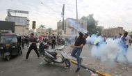 An Iraqi protester throws back a tear gas canister amid clashes with security forces during an anti-government demonstration in Iraq's capital Baghdad on October 27, 2019.   AFP 