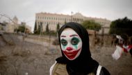 A Lebanese woman with her face painted with the character of the Joker takes part in a protest in downtown Beirut on October 23, 2019.  AFP / Patrick Baz 