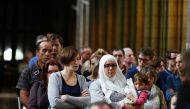A Muslim woman carries a child as people attend a Mass in tribute to priest Jacques Hamel in the Rouen Cathedral on July 31, 2016. AFP