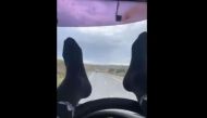 The two-and-a-half minute clip shows the driver with both feet in long black socks on the steering wheel navigating with his calves on the slow lane of a two-lane highway with apparent ease