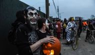  A man poses with a pumpkin while people in costume ride bicycles during the annual Bike Kill event on October 26, 2019 in New York City.  Stephanie Keith/Getty Images/AFP