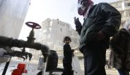 Syrians standing next to water faucets as they fill jerrycans in al-Shaar neighbourhood, Aleppo on January 21, 2017. AFP / Louai Beshara