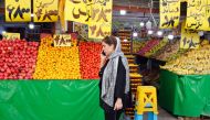 An Iranian woman speaks on her mobile phone as she walks past a fruit shop in central Tehran on November 7, 2019. AFP 