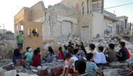 Syrian puppeteer Walid Abu Rashed performs a puppet act for children amid the rubble of damaged buildings in Syria's northwestern city of Saraqib in the Idlib province on September 29, 2019. AFP / Zein Al Rifai 