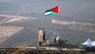 A view from the Israeli side of the border shows Jordanian soldiers praying in front of a national flag during a ceremony at the Jordan Valley site of Naharayim, also known as Baqura, east of the Jordan River on November 11, 2019.  AFP / Menahem Kahana
 