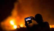 A woman uses her mobile phone to film as a forest fire burns out of control in Las Manchas on the southwestern part of La Palma island, Spain, early August 5. 2016. Reuters / Borja Suarez