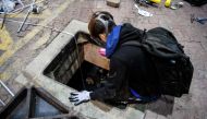 A protester climbs down into a sewer entrance as he and others try to find an escape route from the Hong Kong Polytechnic University in the Hung Hom district of Hong Kong, early morning on November 19, 2019. AFP / Anthony Wallace 