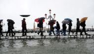 People walk on a catwalk in the flooded St Mark Square during a period of seasonal high water in Venice, Italy November 12, 2019. Reuters / Manuel Silvestri