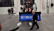 Britain's Prime Minister and Conservative leader Boris Johnson walks past a Union flag-themed JCB, with the words 