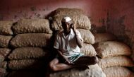 A labourer talks on his mobile phone as he sits on sacks of onions at a wholesale market in Mumbai, India February 15, 2018. Reuters/Francis Mascarenhas