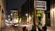 Council workers attach a polling sign to a lamp post in central London as polling stations open for a general election in London on December 12, 2019. AFP / DANIEL LEAL-OLIVAS