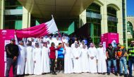 The QOC Secretary-General, officials and athletes posing for a photograph with the Qatar flag during the event.