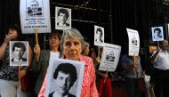 In this file photo taken on April 09, 2014 Beatriz Cantarini de Abriata, mother of Hernan Abriata, arrested in 1976 in Argentina and missing, holds a portrait of her son next to relatives and friends holding also the portrait of former Argentine police of