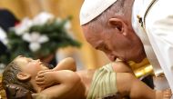 Pope Francis kisses a figurine of baby Jesus during a mass on Christmas eve on December 24, 2019, at St Peter's basilica in the Vatican. AFP / Alberto Pizzoli 