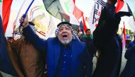 Iraqis wave Hashed Al-shaabi armed network flags on December 30, 2019, during a demonstration to denounce the previous night's attacks by US planes on several bases belonging to the Hezbollah brigades near Al-Qaim, an Iraqi district bordering Syria.  AFP 