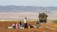 Syrian soldiers in a truck past people sitting in a field with harvested aubergines in the eastern countryside of the city of Qamishli in the northeastern Hasakah province on November 5, 2019. AFP / Delil Souleiman