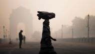 A woman balances a load on her head as she crosses a street near India Gate in heavy smoggy conditions in New Delhi on December 6, 2019. AFP / Jewel Samad