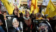 A Palestinian woman gestures as others hold pictures of president Mahmoud Abbas and late leader Yasser Arafat during a rally marking the 55th anniversary of Fatah's founding, in Gaza City, January 1, 2020. Reuters/Ibraheem Abu Mustafa