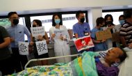 FILE PHOTO: A patient is wheeled past as healthcare staff hold posters in a human chain to protest against police brutality at Queen Mary Hospital, in Hong Kong, September 2, 2019. Reuters / Anushree Fadnavis