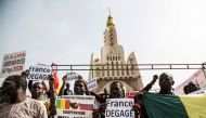 People hold up banners reading 'France get out' as they gather around the independence monument during a protest against French and UN forces based in Mali organized by Malian organization 'Yerewolo debout sur les remparts ' or 'Yerewolo standing on the r