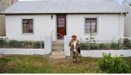 Pauline Cloete poses in front of her house for a photo in Elim in the Western Cape, South Africa, 11 December 2019. Thomson Reuters Foundation/Kim Harrisberg