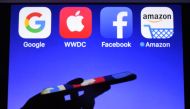 A smartphone being operated in front of GAFA (acronym for Google, Apple, Facebook and Amazon) logos as background in Hédé-Bazouges, western France on September 28, 2017. AFP / Damien Meyer. 