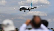 Visitors watch as a Boeing 737 Max lands after an air display during the Farnborough Airshow, south west of London on July 16, 2018. AFP / Ben Stansall