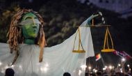 Romanians chant slogans next to a giant statue picturing the symbol of justice during a demonstration on August 11, 2018 in Bucharest. AFP / Daniel Mihailescu