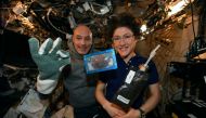 In this photo made available by U.S. astronaut Christina Koch and Italian astronaut Luca Parmitano pose for a photo with a cookie baked on the International Space Station Twitter: @Astro_Christina