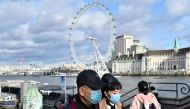 A couple wear face masks as they walk along the Thames embankment in central London on January 28, 2020. Around 1,500 people who came to Britain from the Chinese epicentre of the coronavirus epidemic in the past two weeks must put themselves in isolation,