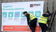 Workers install a banner with hygiene recommendations outside the Mobile World Congress MWC venue on February 12, 2020 at the Fira Barcelona Montjuic centre in Barcelona.  AFP / LLUIS GENE