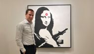 Scott Lynn, CEO and founder of Masterworks, poses next to a Banksy artwork in New York, U.S., February 11, 2020. Picture taken February 11, 2020. REUTERS/Aleksandra Michalska 