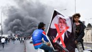 Iraqi demonstrators lift a poster of premier-designate Mohammad Allawi with the mention 