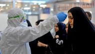 The body temperature of an Iraqi woman returning from Iran is measured upon her arrival at the Najaf International Airport on February 21, 2020, after Iran announced cases of coronavirus infections in the Islamic republic. / AFP / Haidar HAMDANI
