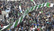 Algerian protesters march national flags during their weekly anti-government demonstration in the capital Algiers, on February 21, 2020. / AFP / RYAD KRAMDI